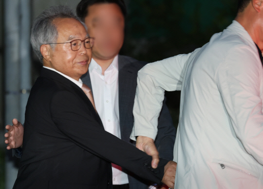 직원을 강제 추행한 혐의로 징역 3년을 선고받은 오거돈 전 부산시장이 26일 오전 만기 출소로 풀려나 부산 사상구 부산구치소를 나서고 있다. 취재진 질문이 이어지자 오 전 시장의 지인은 그의 손을 이끌고 차량에 빠르게 태웠다.   [연합뉴스]